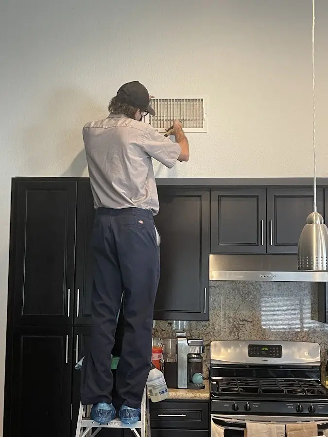 Technician inspecting an air vent during HVAC service in Forrest City